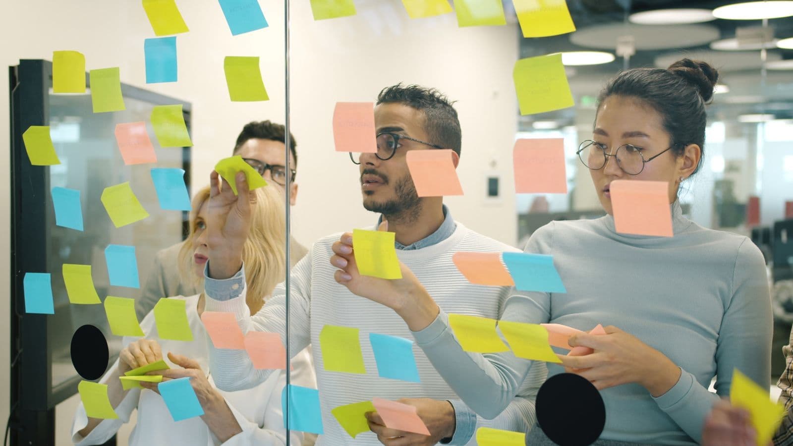 Une équipe organise les étapes d'un projet sur un mur de notes adhésives
